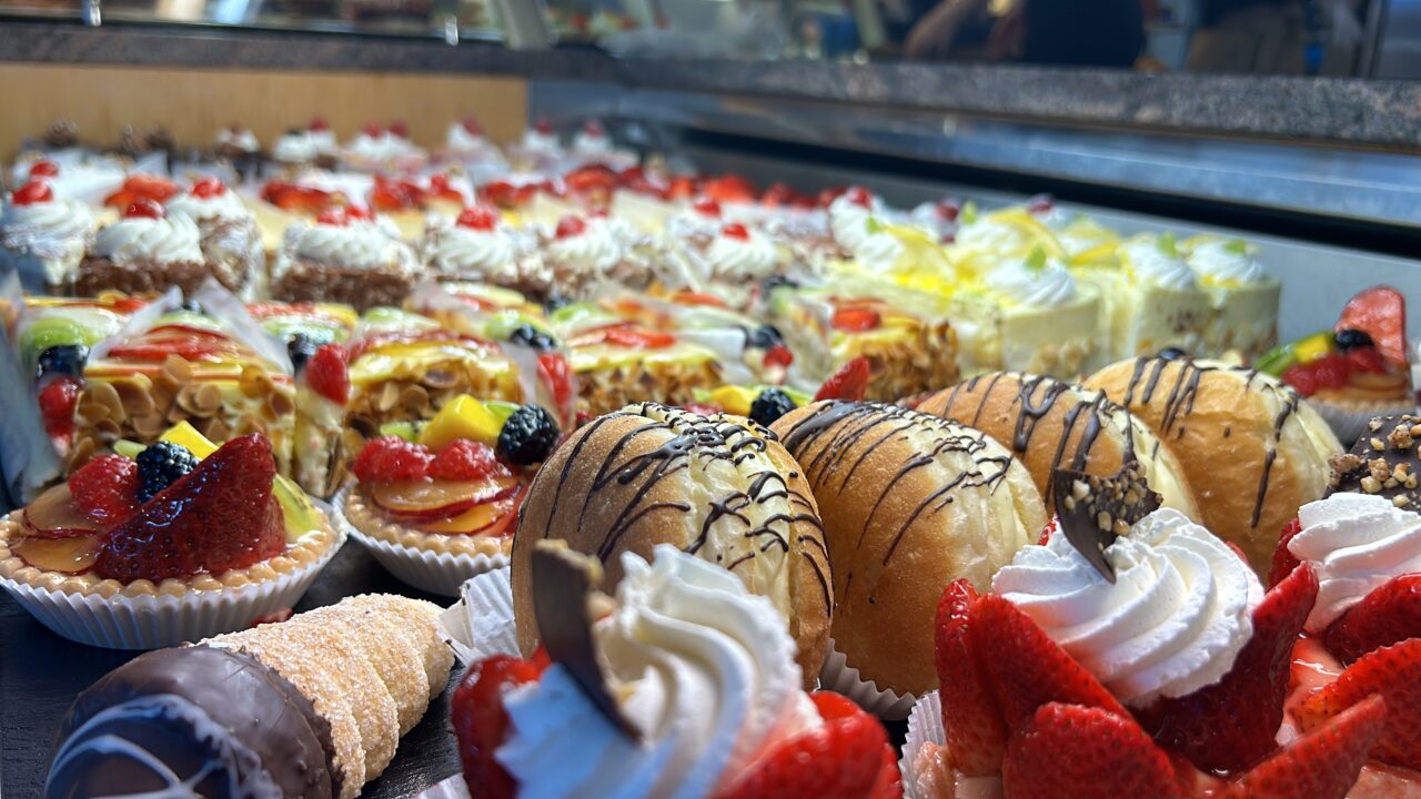 Assortierte süße Backwaren und Törtchen mit frischen Früchten und Schokolade in einer Bäckerei-Auslage.